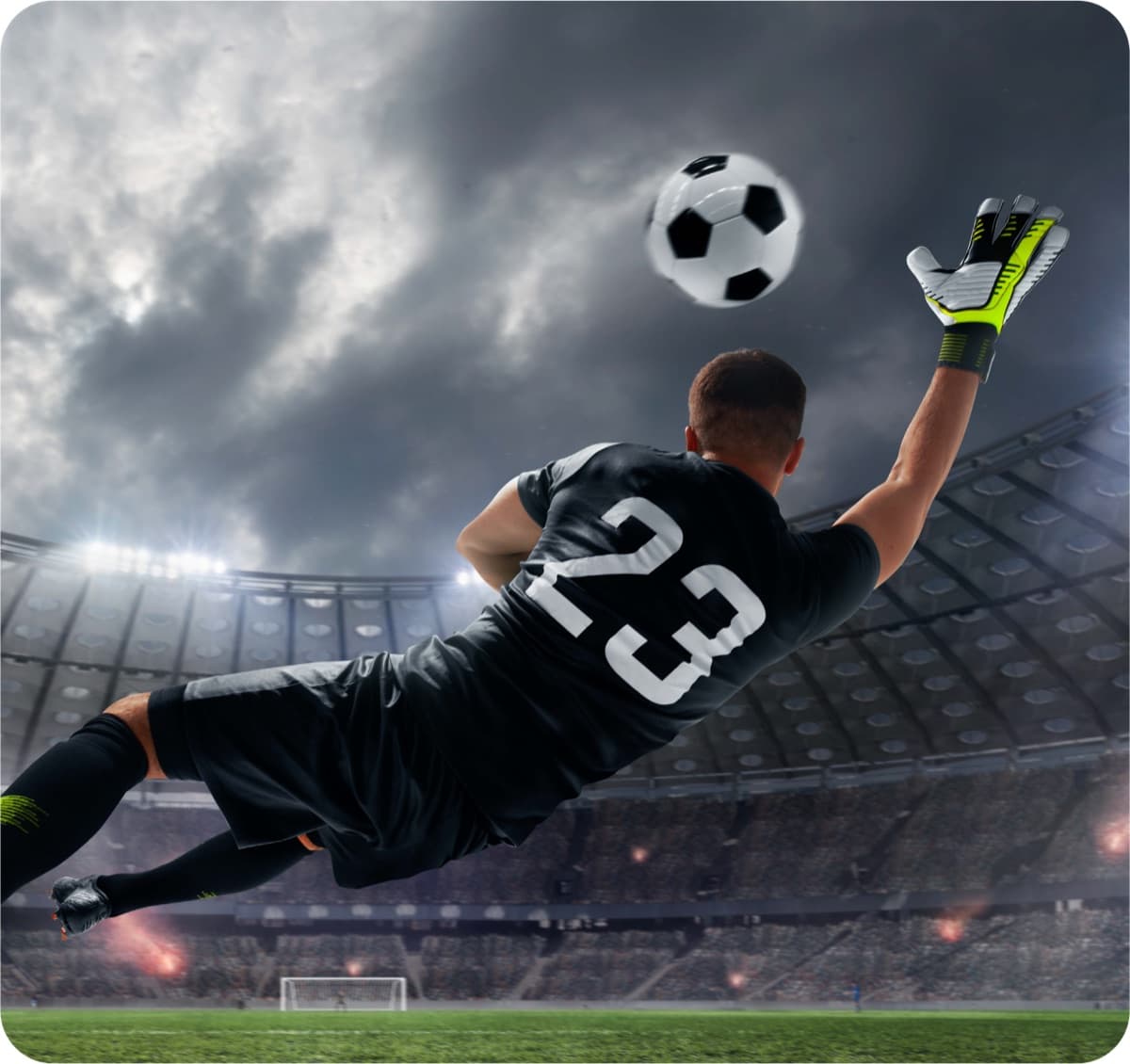 Goalkeeper stretching for the ball in a floodlit stadium